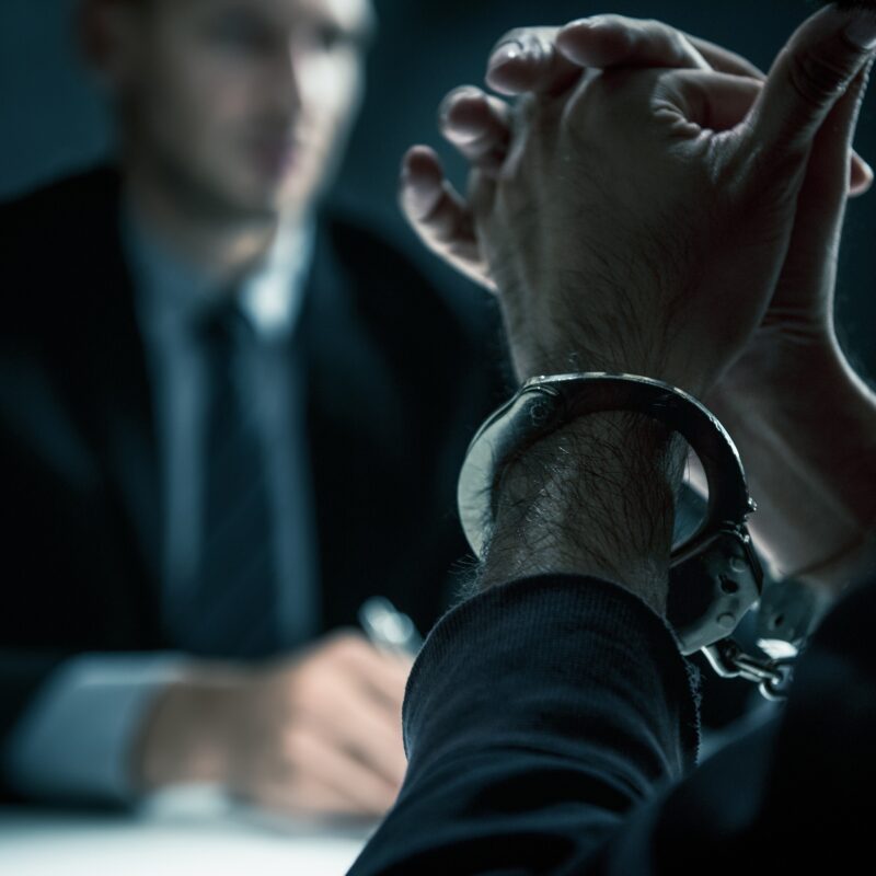 criminal-man-with-handcuffs-in-interrogation-room